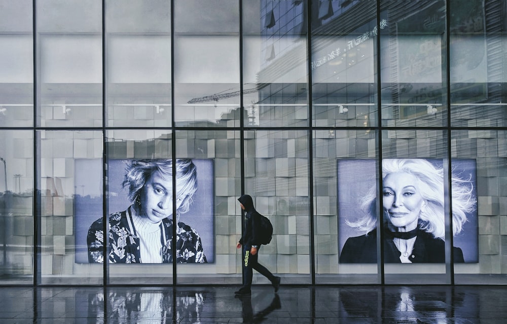 person wearing hoodie walking beside portrait of two women