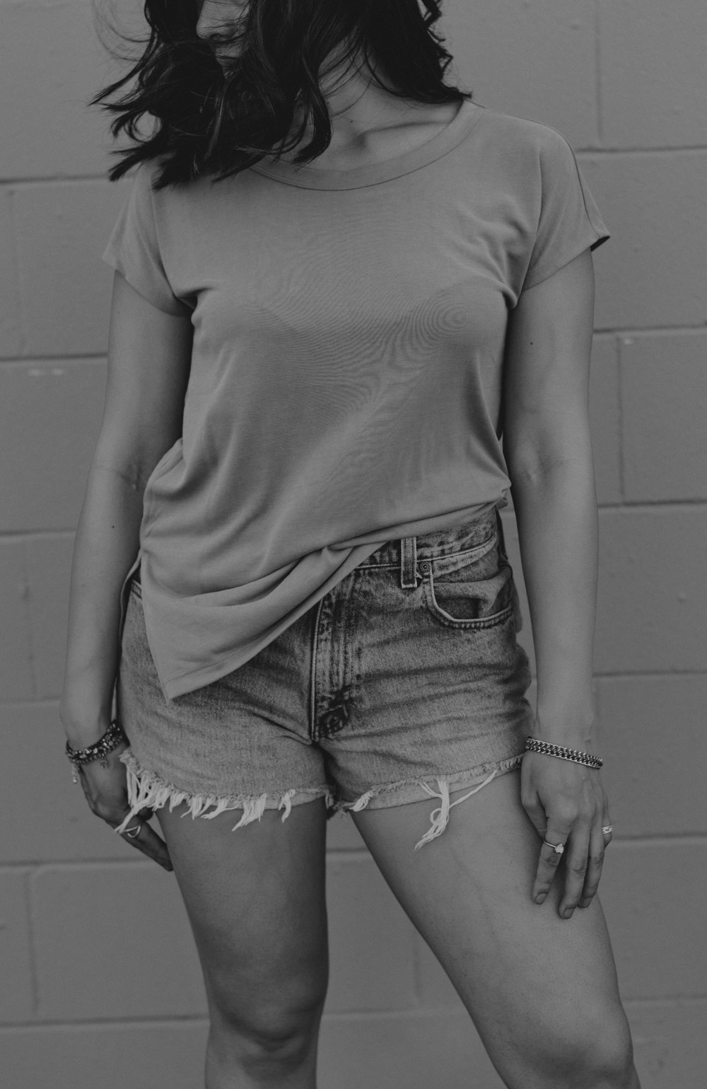 Tシャツとデニムのショートパンツを着た女性のグレースケール写真