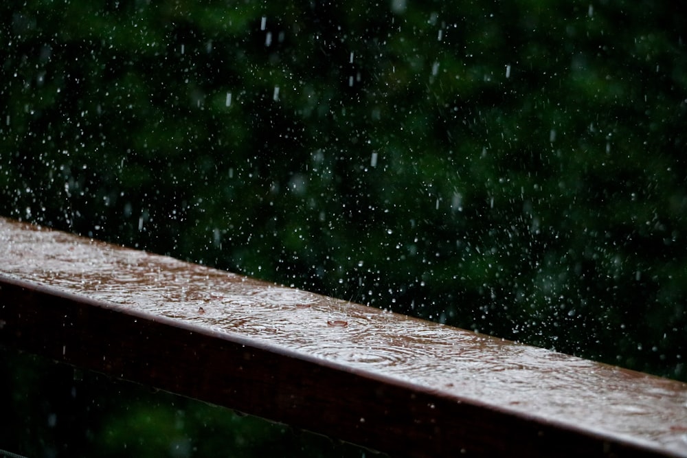 a wooden bench with rain falling down on it