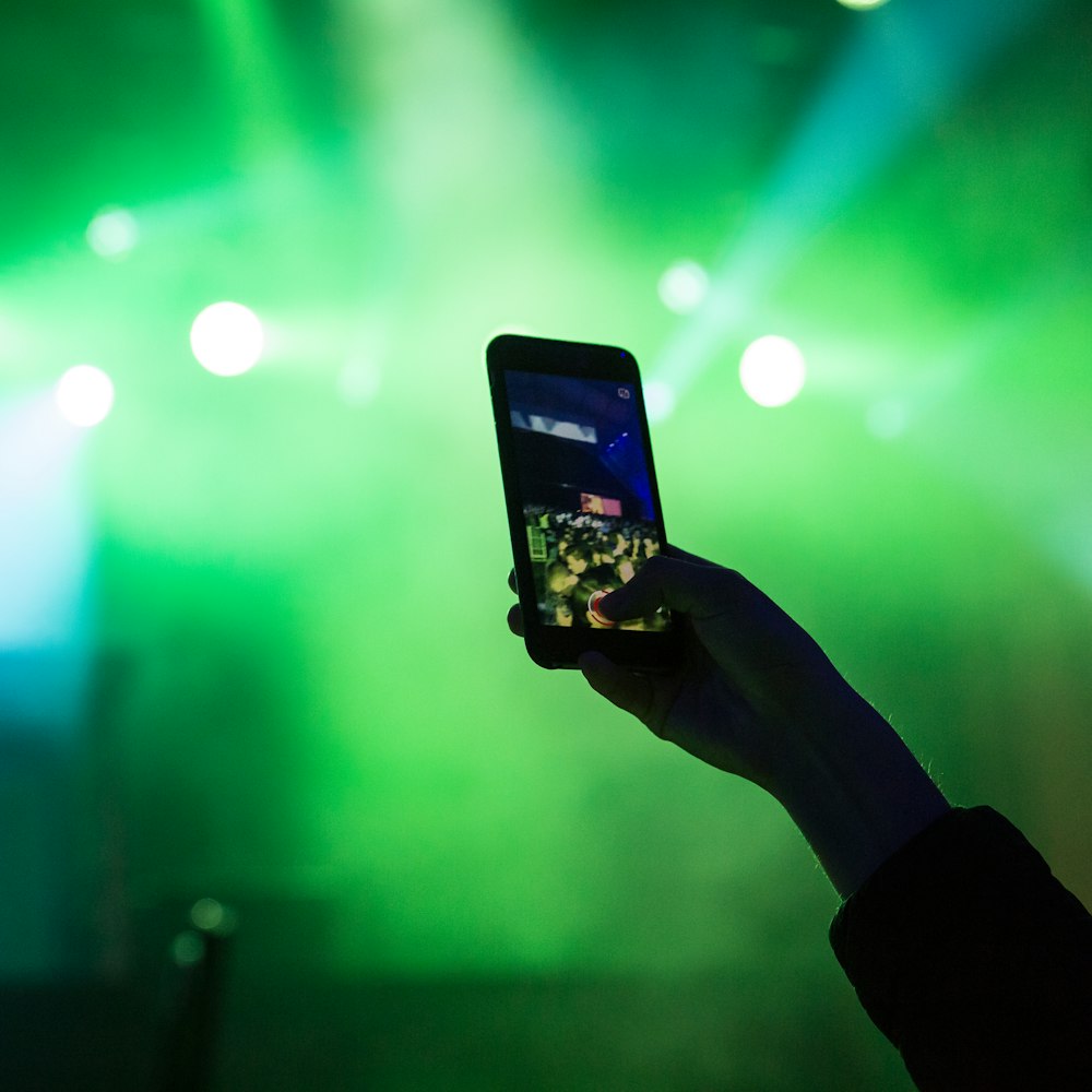 person's hand holding turned-on smartphone