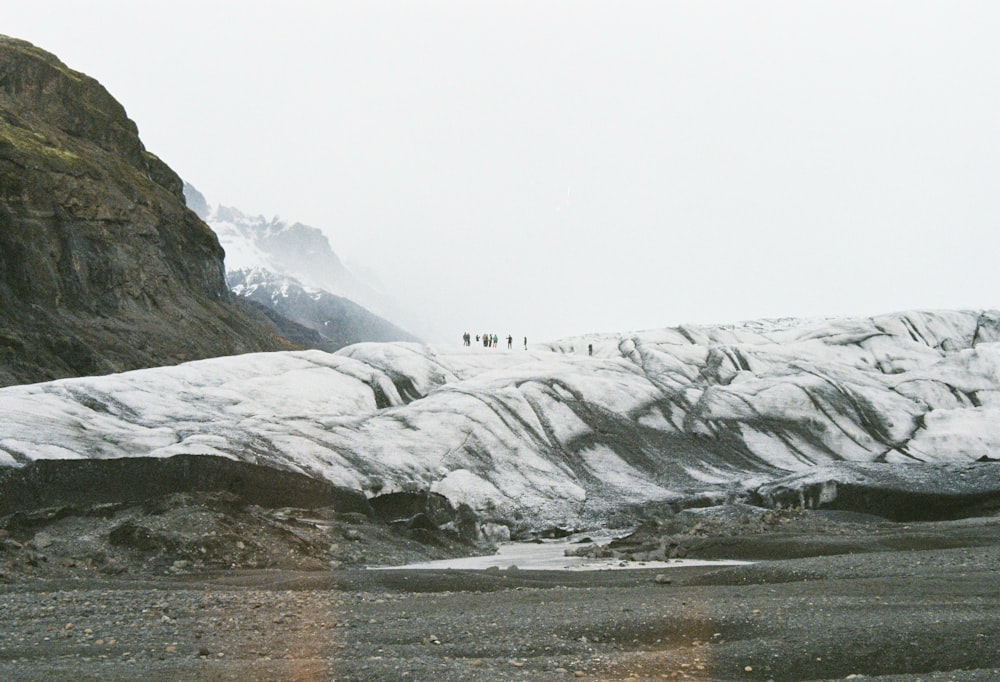 personas de pie en montañas cubiertas de nieve durante el día