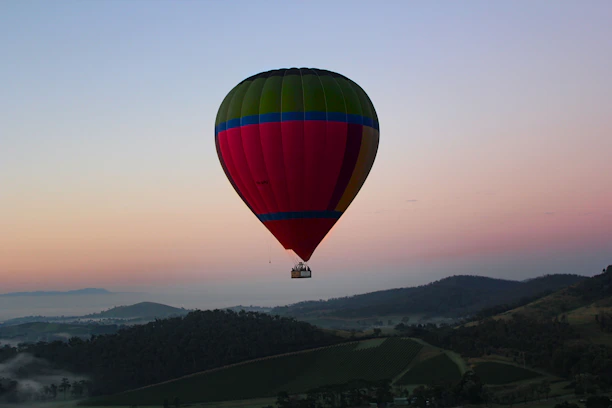 A colorful hot air balloon soaring gently over a serene countryside at sunrise.