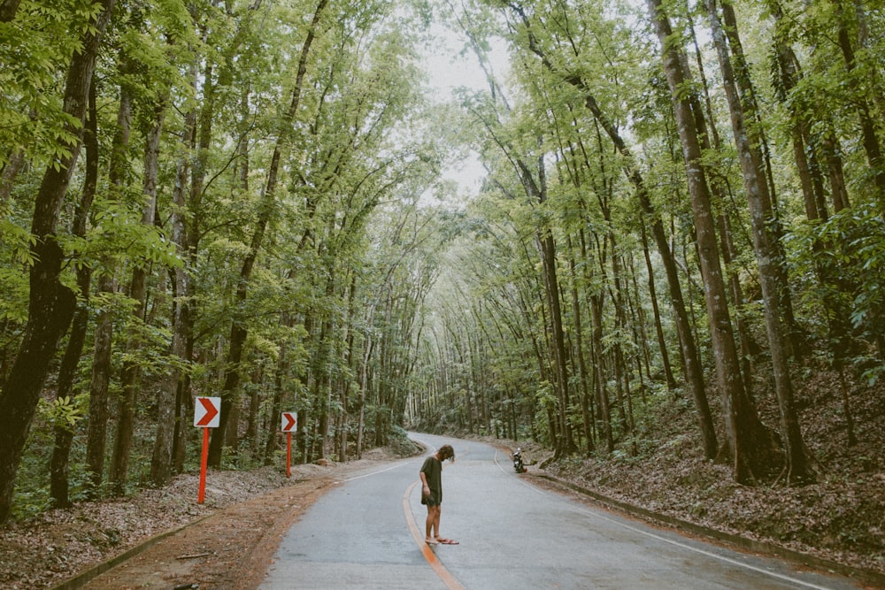 person standing in the street with trees beside it