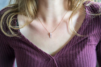 A model wearing a statement necklace with burgundy and gold accents in natural light.