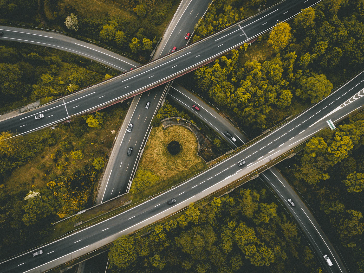 Aerial view of intersecting highway bridges through a forest canopy — public works and transportation infrastructure