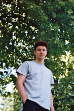 man putting his hand inside his pocket under the tree