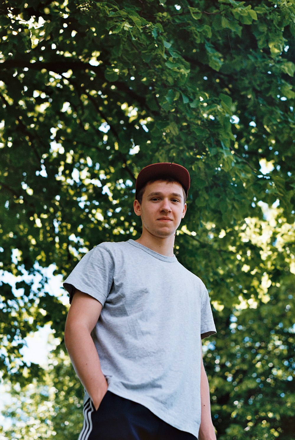 man putting his hand inside his pocket under the tree