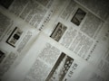 A close-up of a newspaper with multiple pages spread out. The text is written in a non-Latin script, possibly Chinese. There are also images within the articles, including one with the word 'NEWS'. The pages are slightly overlapping, creating an organized yet informal layout.