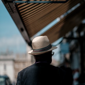 man wearing white straw hat and black shirt walking on the street