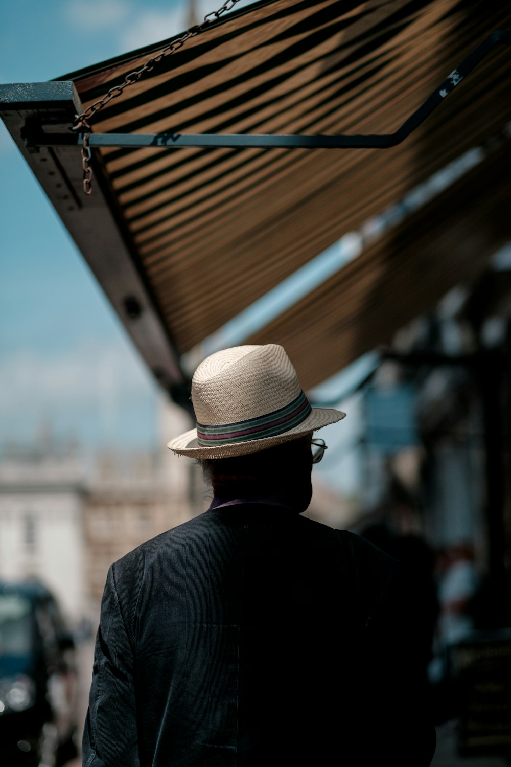 Homem vestindo chapéu de palha branco e camisa preta andando na rua