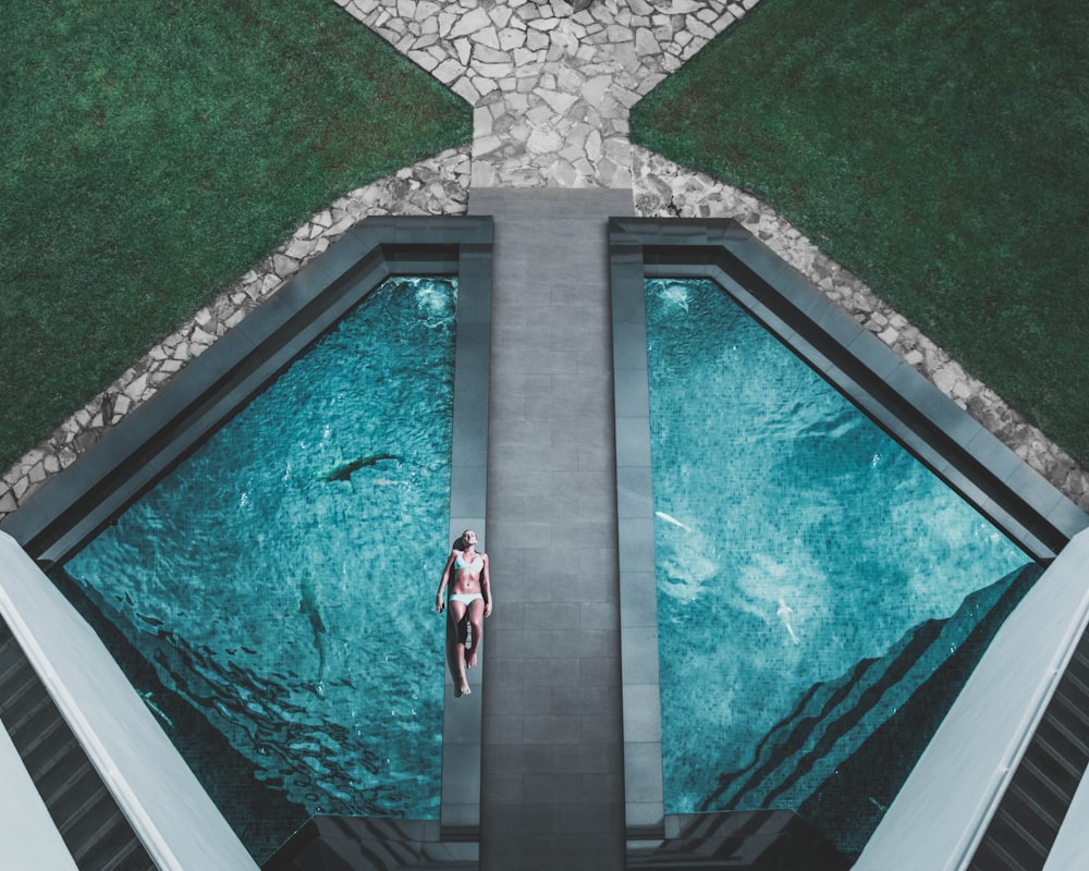 Vogelperspektive einer Frau, die neben dem Swimmingpool auf dem Boden liegt