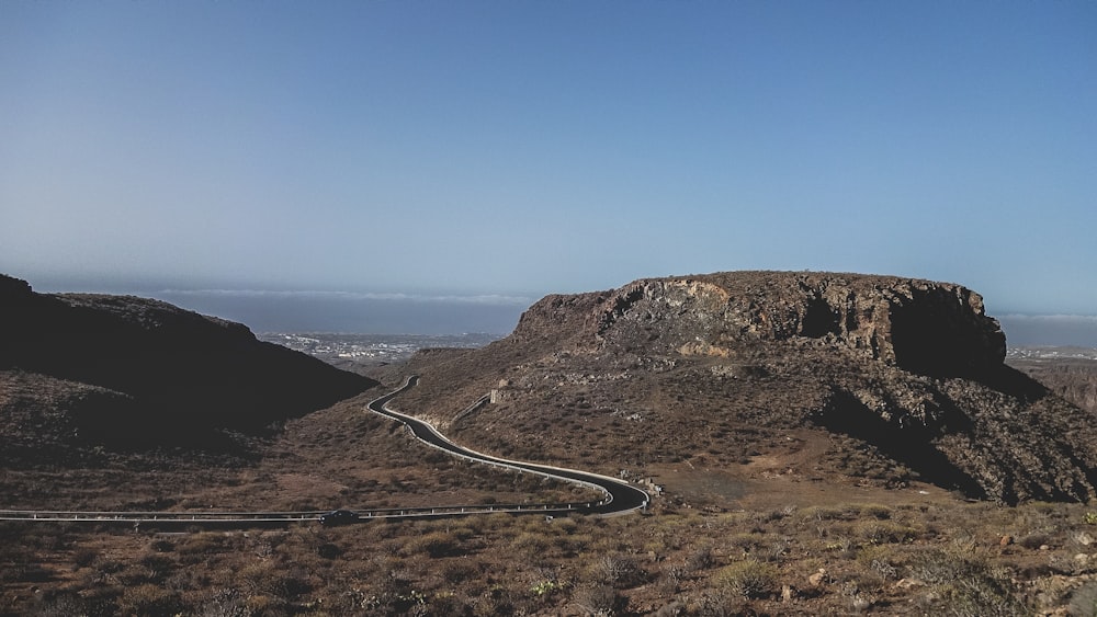 gray asphalt road near brown mountain during daytime