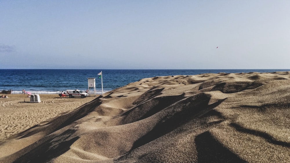 brown sand near body of water during daytime