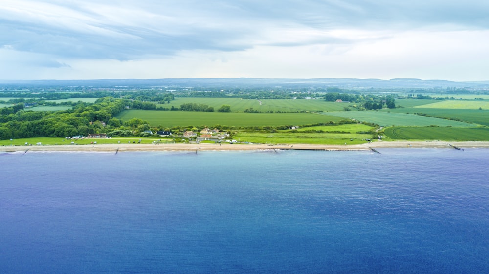 aerial photography of green fields near beach during daytime