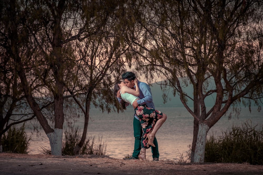 couple kissing in front of trees