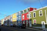 A neat row of residential buildings with freshly painted exteriors under a clear sky.