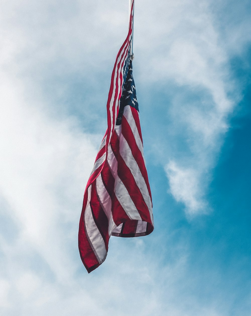 흰 구름 아래를 날고 있는 미국의 국기