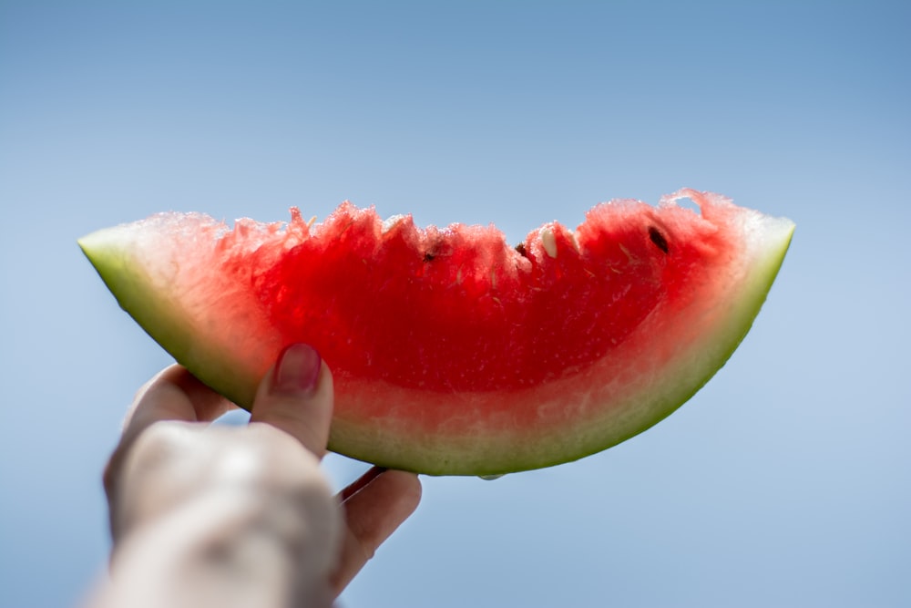 Person, die in Scheiben geschnittene Wassermelone hält