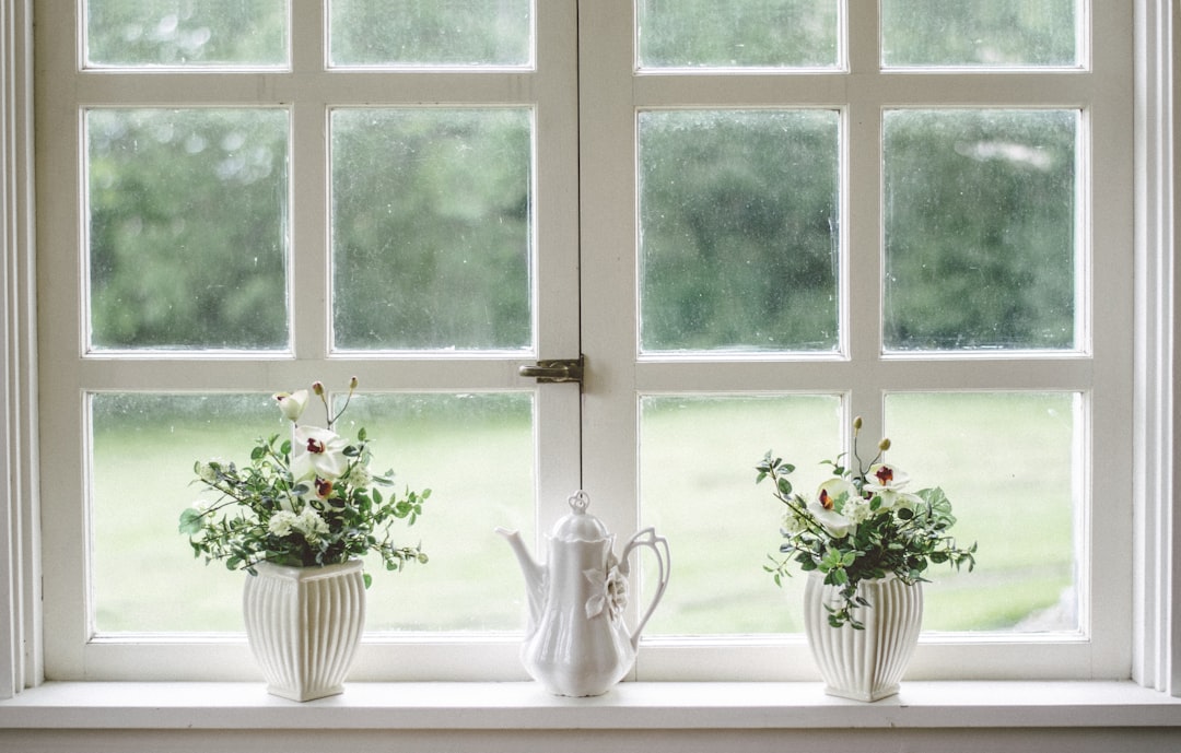  white teapot and tow flower vases on windowpane window