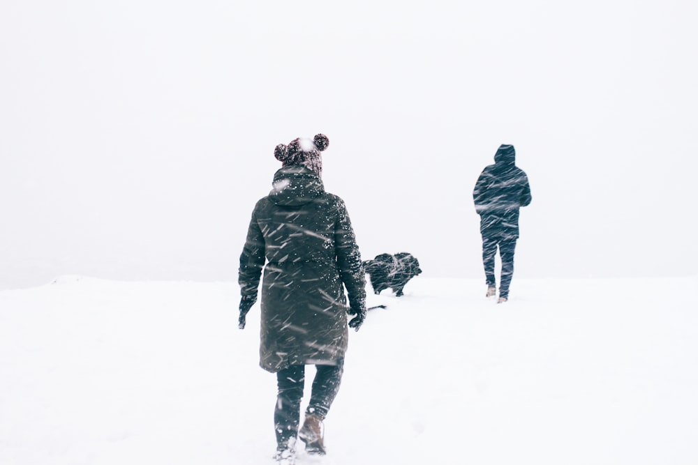 검은 재킷을 입은 두 사람이 눈 덮인 날씨를 걷는 사진