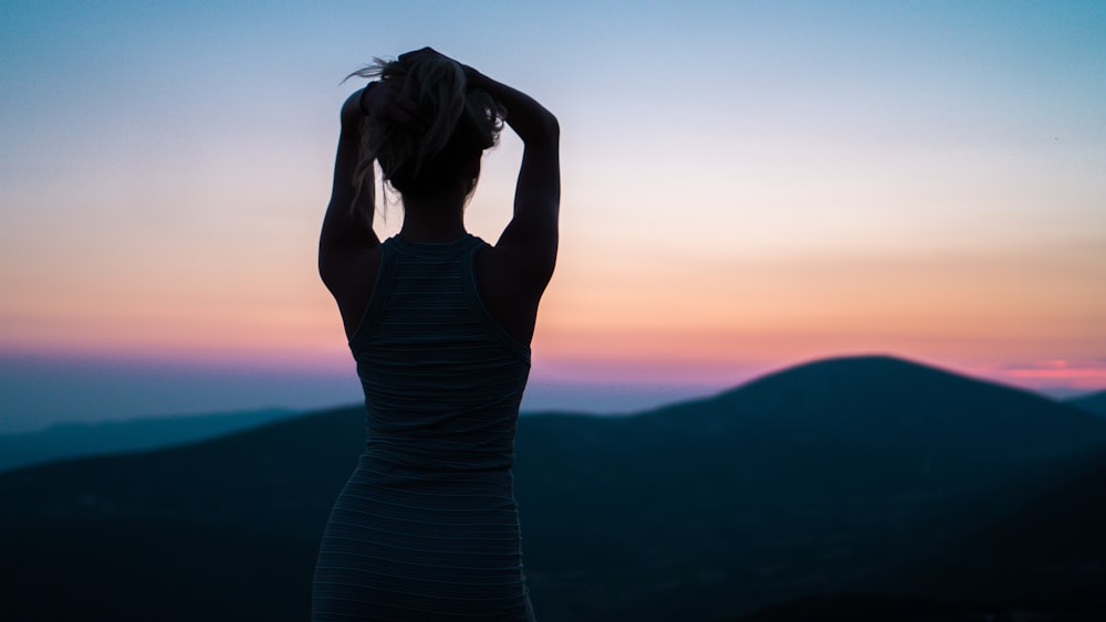 silhouette of woman standing near mountain peak