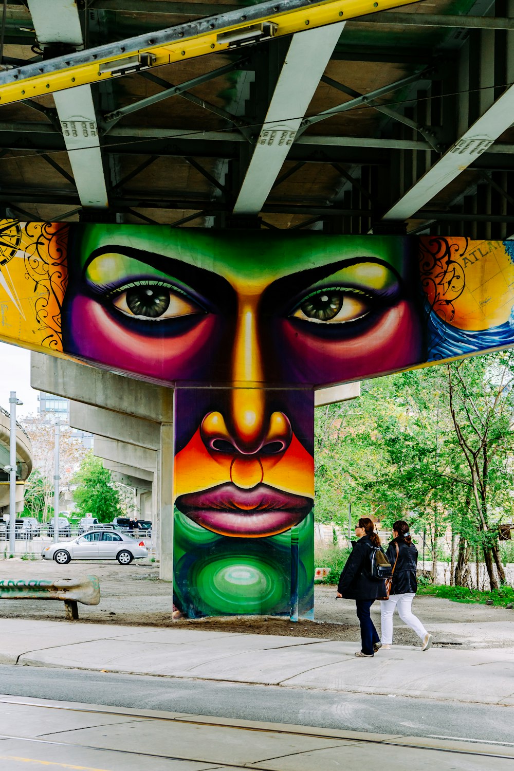 two woman walking under bridge