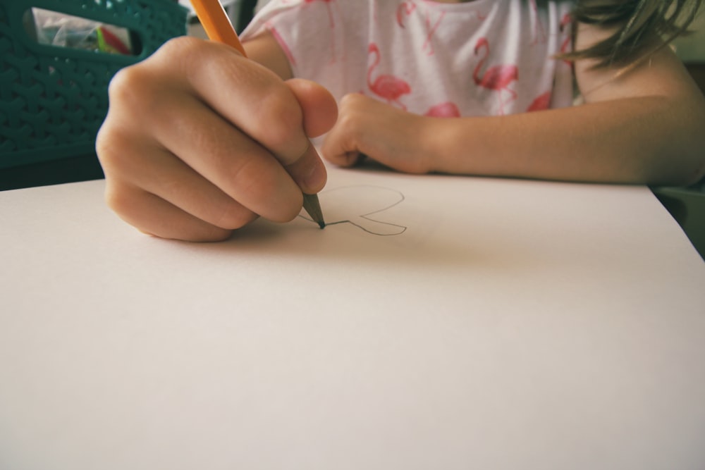 Uma garotinha desenhando uma imagem no papel com um lápis.