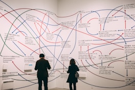 a couple of people standing in front of a wall