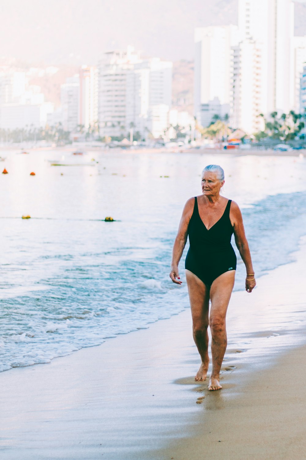 a woman walking along a beach next to the ocean