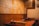 A cozy restaurant interior featuring wooden walls adorned with numerous signed plaques or pieces of paper. Two tables are visible with sauce containers and cooking equipment, suggesting a setting for communal dining or a barbecue style restaurant.