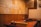 A cozy restaurant interior featuring wooden walls adorned with numerous signed plaques or pieces of paper. Two tables are visible with sauce containers and cooking equipment, suggesting a setting for communal dining or a barbecue style restaurant.