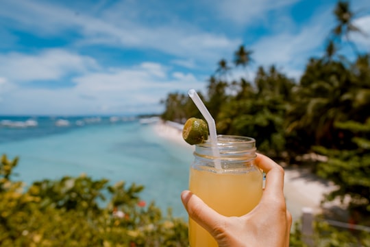 person holding mason jar with filled with juice at daytime in Alona Beach Philippines