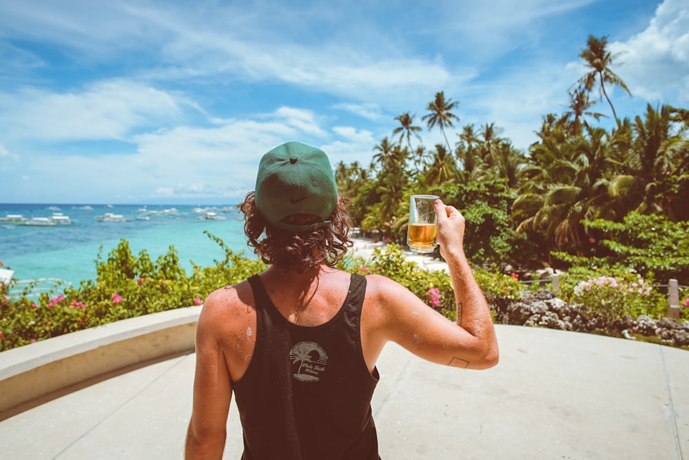 hombre con camiseta sin mangas negra sosteniendo un vaso transparente para beber