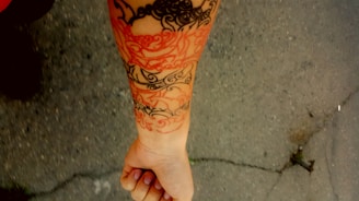 Close-up of a bold black and red custom tattoo on forearm in a dimly lit studio