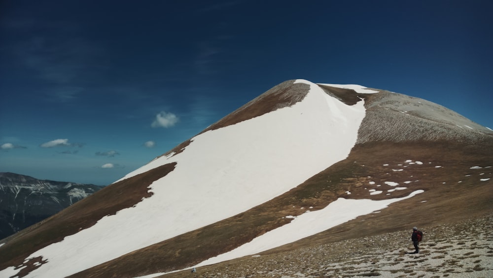 person standing on sand and hill at distance