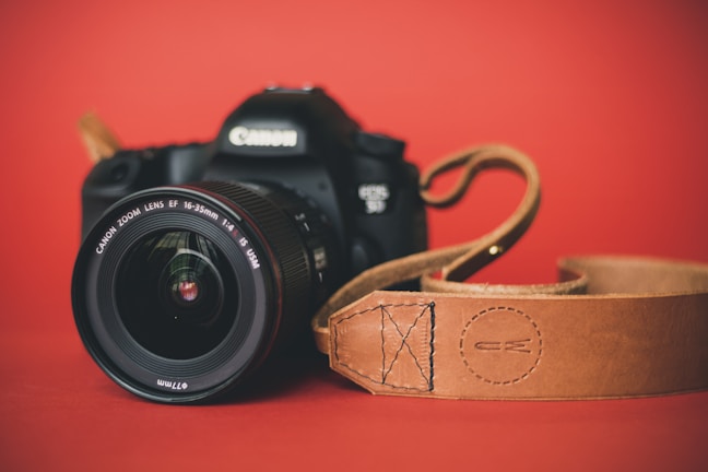 Close-up of a sleek DSLR camera with a vintage leather strap.