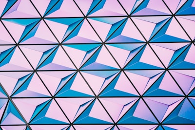 A geometric pattern composed of interconnected triangular shapes, each containing a pyramid-like structure with varying shades of blue and pink.