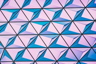 A geometric pattern composed of interconnected triangular shapes, each containing a pyramid-like structure with varying shades of blue and pink.