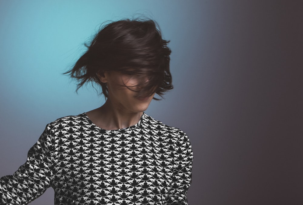 Woman wearing a patterned sweater flips her short hair in front of her face