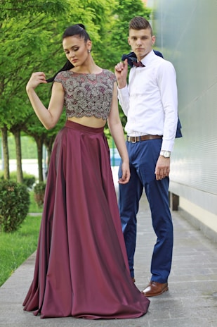 A fashionable man and woman showcasing their coordinated outfits in a park.