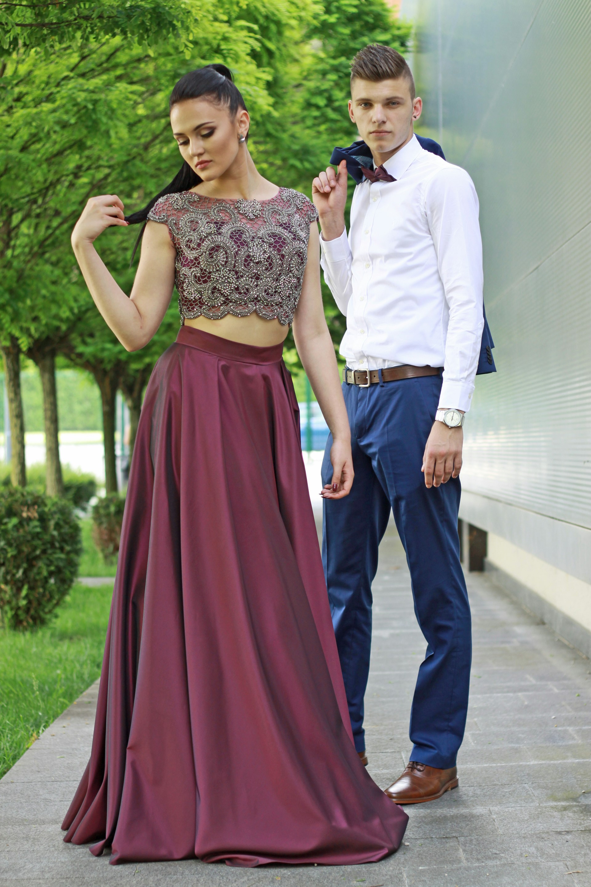 A fashionable couple dressed in coordinating outfits, standing confidently in a luxurious urban setting, embodying modern style.
