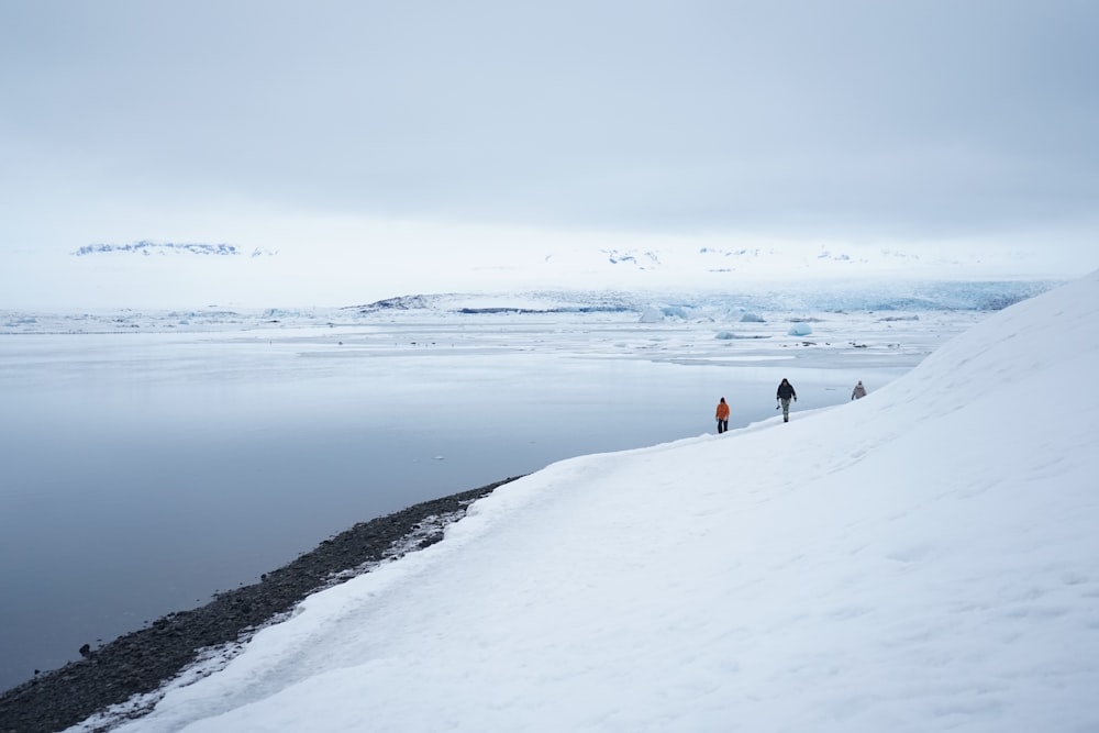 duas pessoas caminhando em terreno coberto de neve