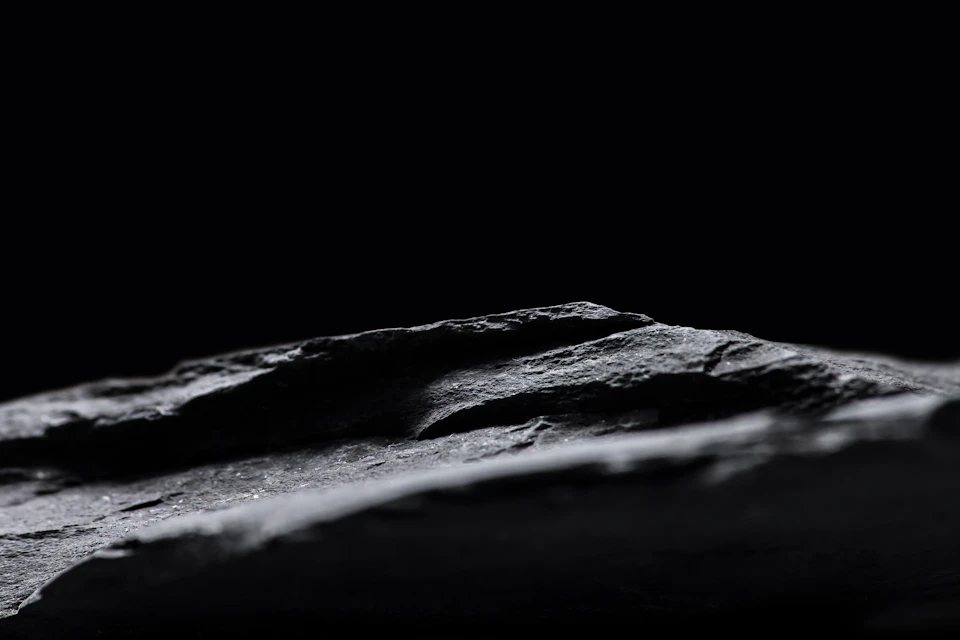 Close-up view of a black, textured rock formation against a gray background