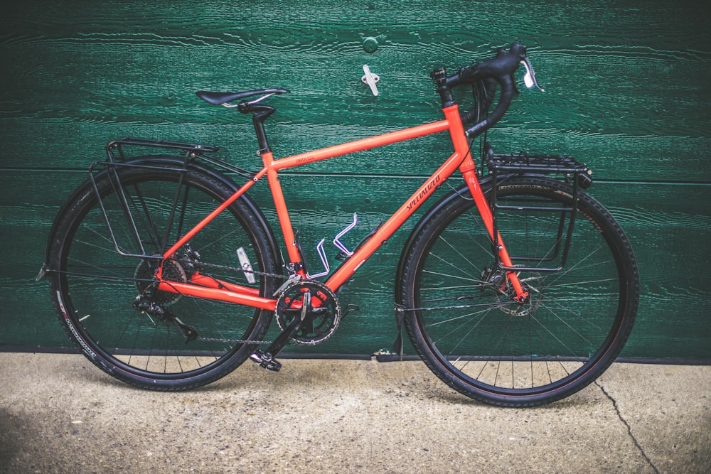 Rotes und schwarzes Rennrad auf grüner Wand