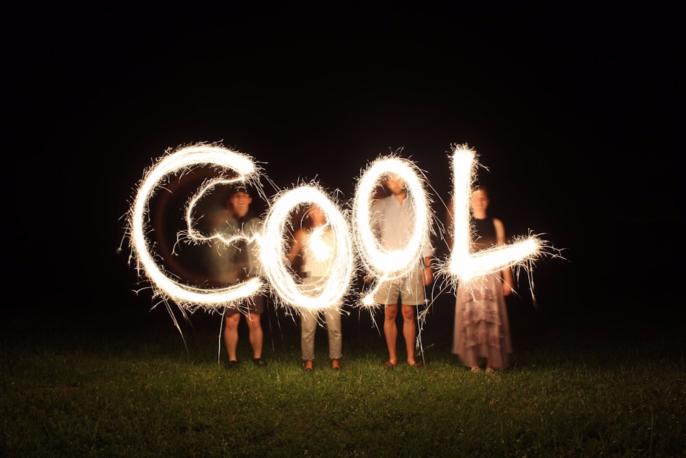 Cuatro personas sosteniendo fuegos artificiales y formando una palabra genial