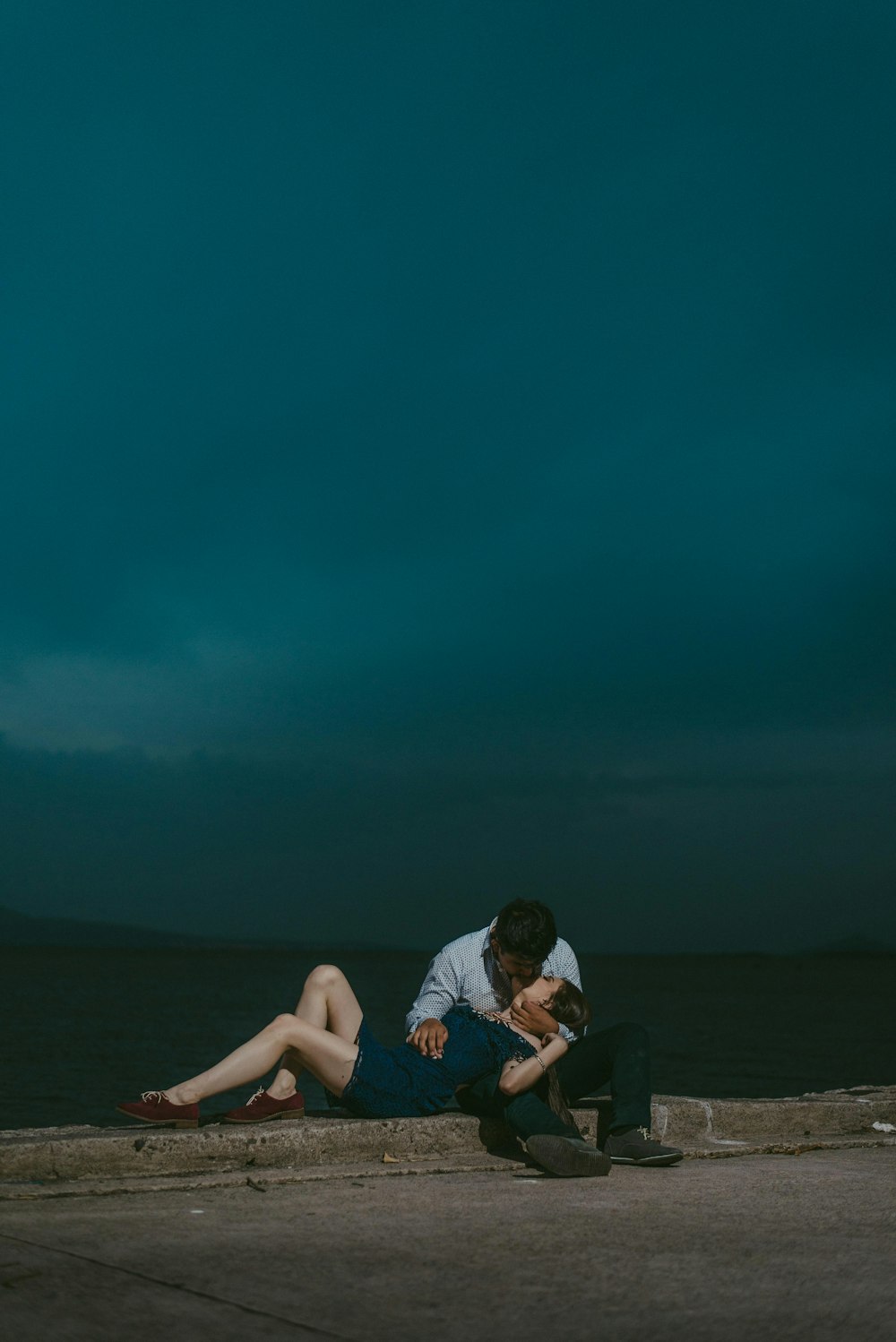 man kissing woman while sitting on railings during night