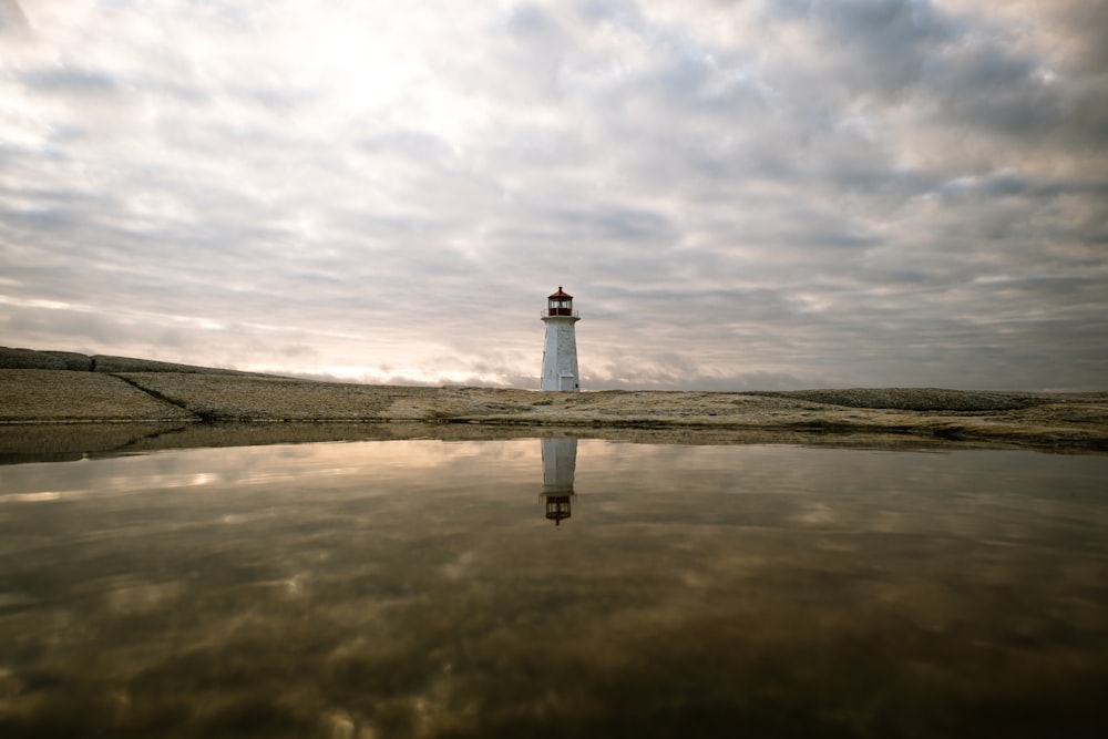 lighthouse reflecting on body of water