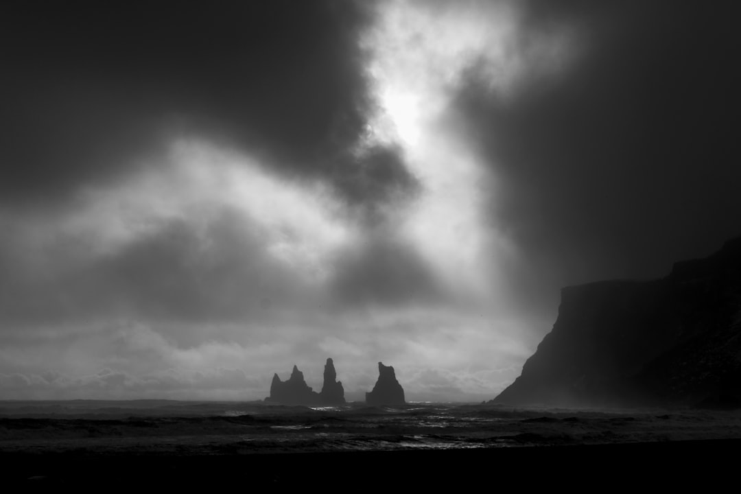 grayscale photo of rock formation surrounded by water