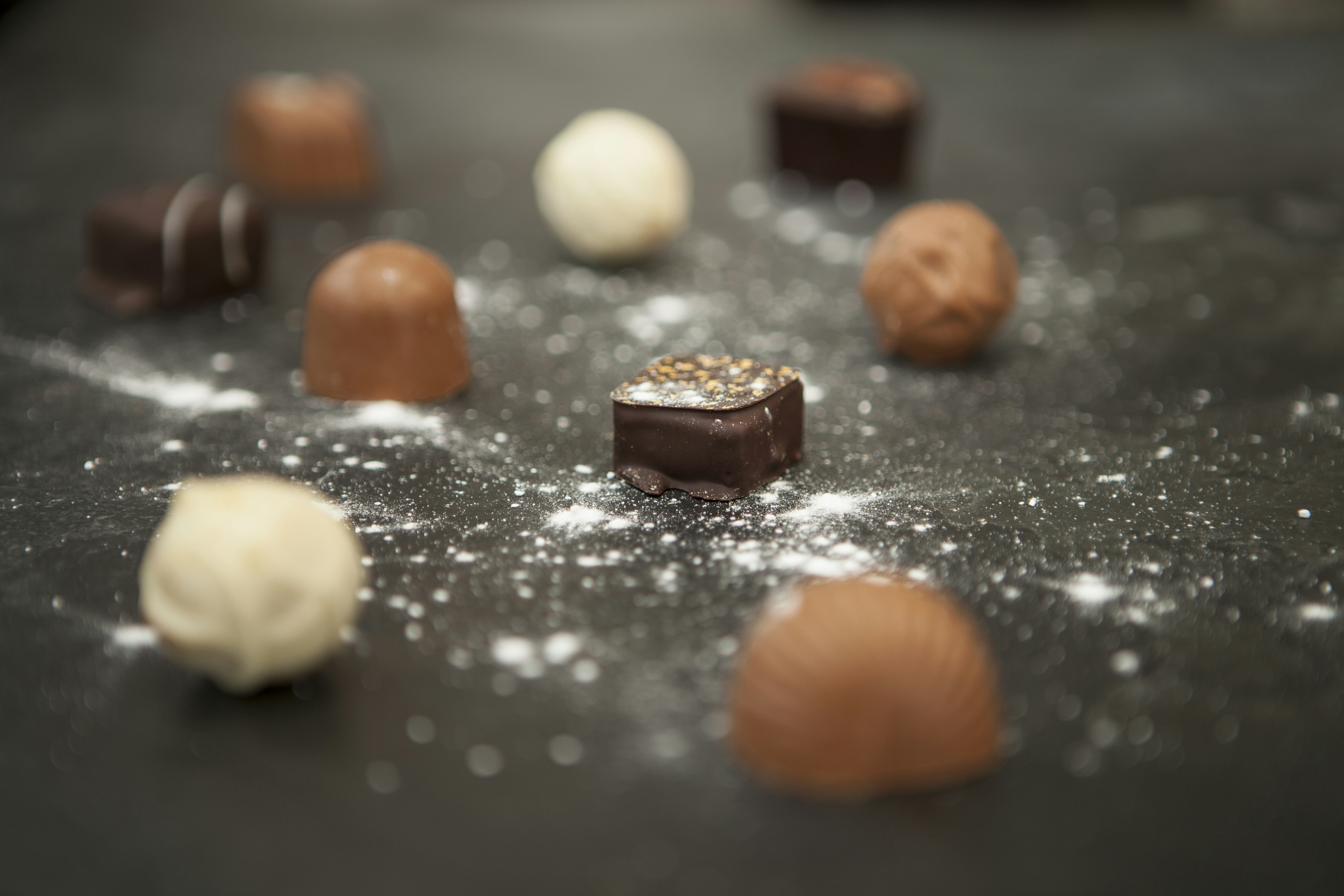 Overhead flat lay of assorted chocolate truffles and pralines on dark surface