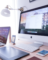 silver iMac near iPhone on brown wooden table